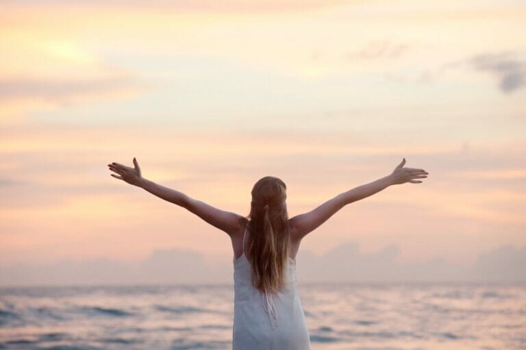 photo of a woman with her arms outstretched in front of the ocean