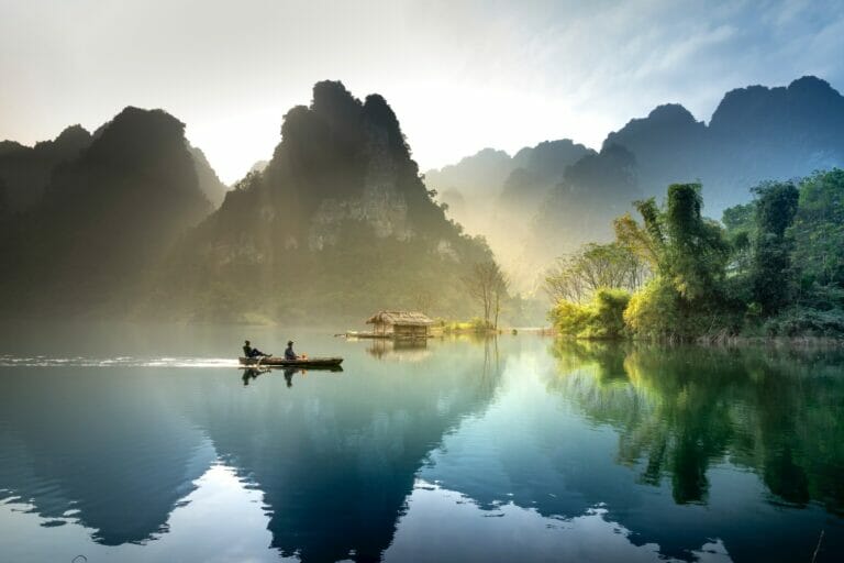photo of men in a boat fishing with mountains int he background