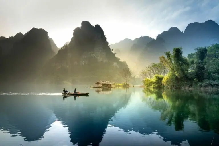 photo of men in a boat fishing with mountains int he background